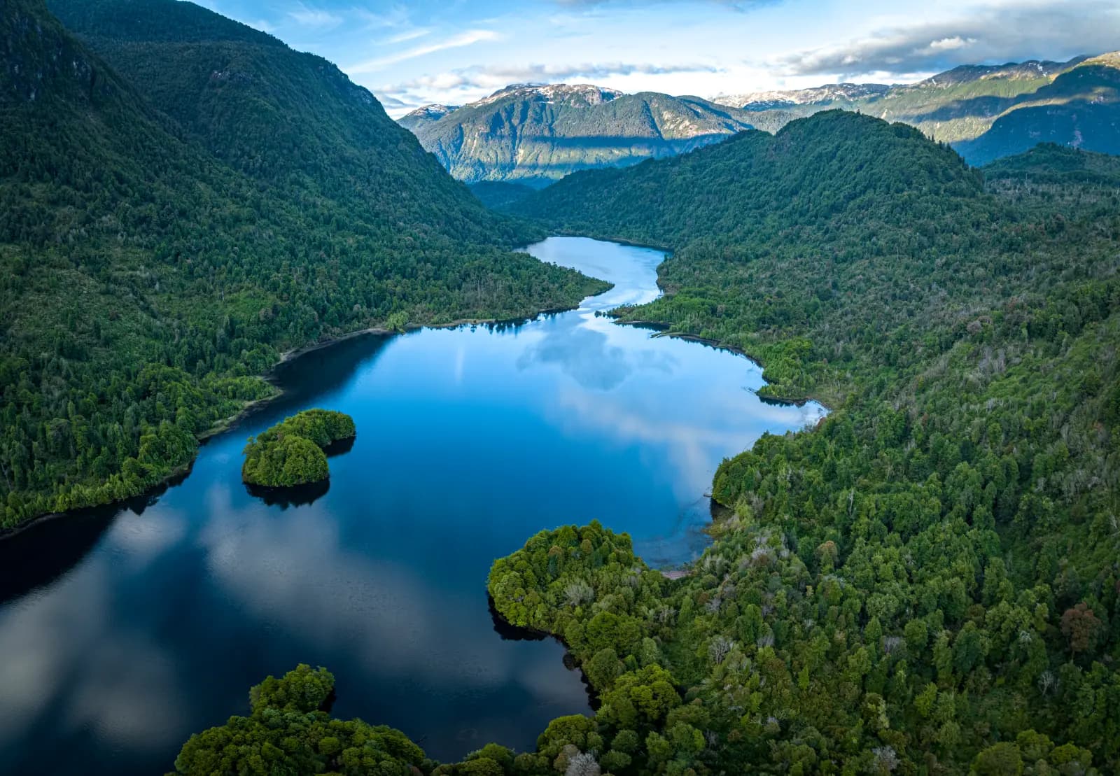 A forested island mirrored on the still turquoise lake